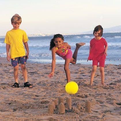 This may contain: three children playing with a ball on the beach