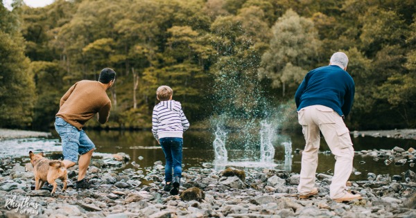 family throwing rocks and skipping stones from a creek shore.