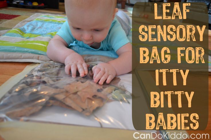 This may contain: a baby laying on the floor playing with some sort of bag for itty bitty babies