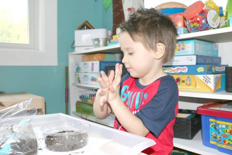 preschooler planting grass in small plastic container