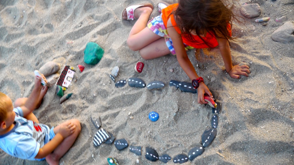 Two kids playing with DIY Car Rock track. on a beach,