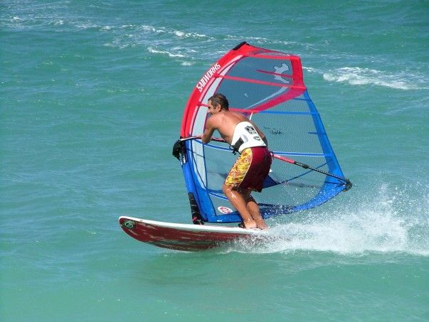This may contain: a man is windsurfing in the ocean on a sunny day with clear blue water