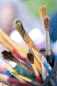 cup of paintbrushes to use to paint ice with salt water or with paint for a playing with ice art activity