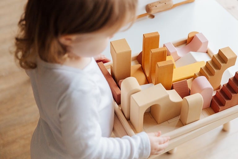 A two-year-old plays with wooden blocks.