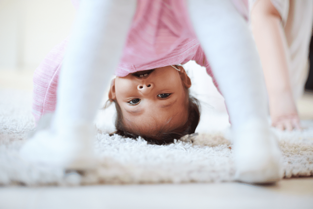 A baby turns upside down to look at the camera.