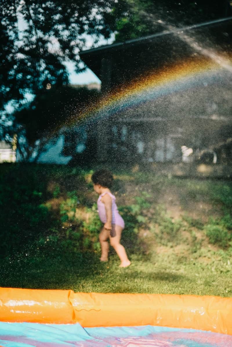 A child plays outside next to a kiddie pool in summer.