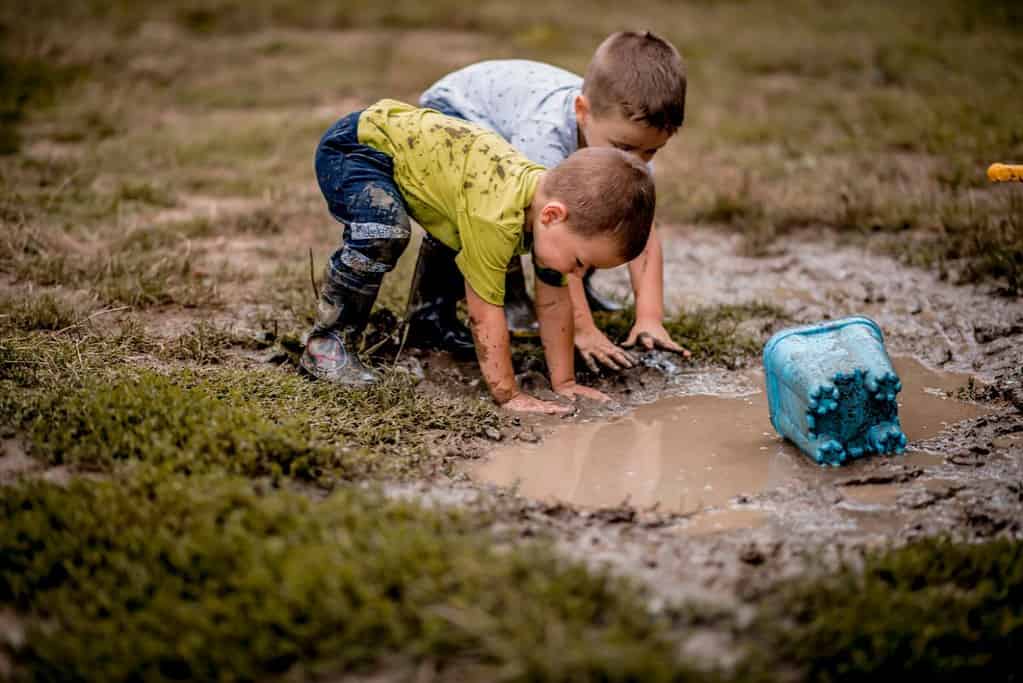 Two young children play in mud on their early childhood program's playground.