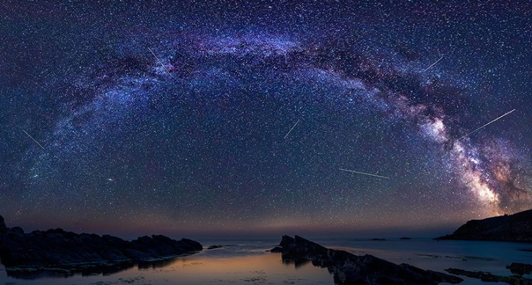 A long exposure of the night sky, showing stars and streaks from meteors