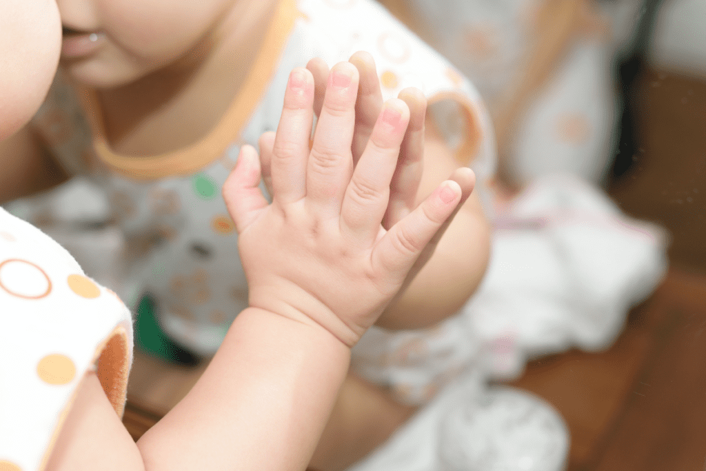 A baby hand pressing against a mirror during sensory play.