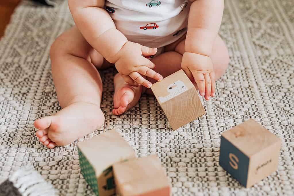 A baby plays with wooden blocks during sensory play.