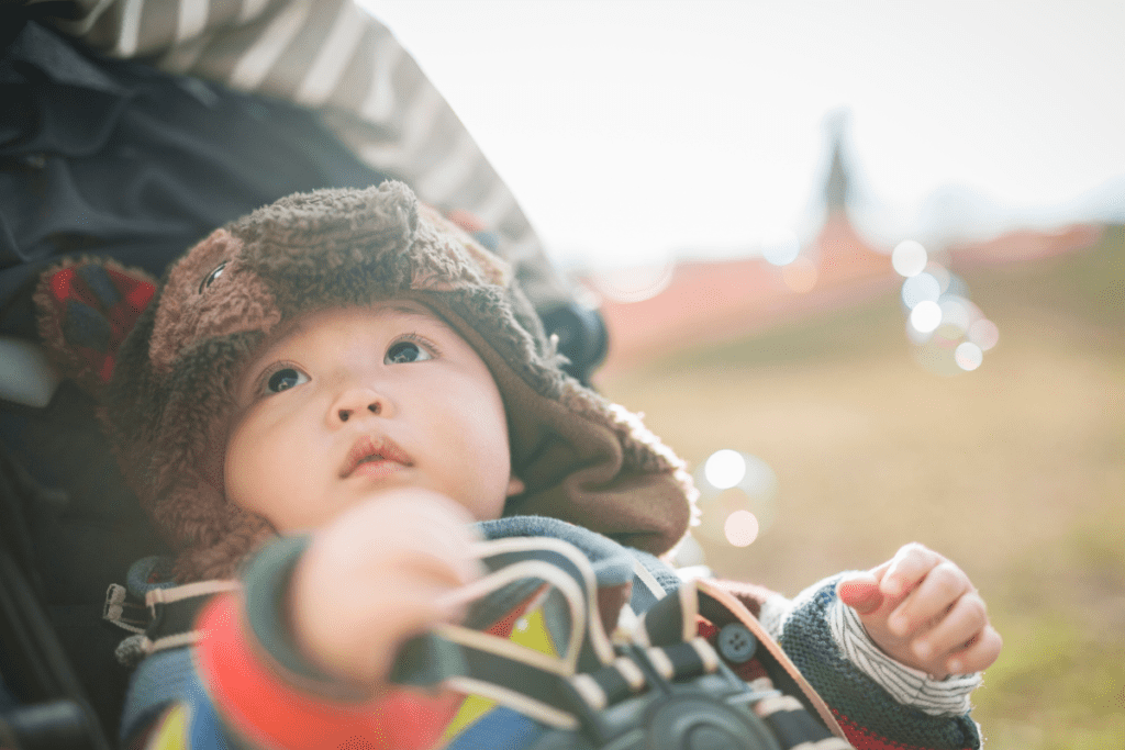 A baby in a stroller is mesmerized by watching bubbles move.