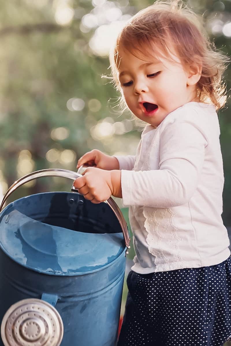 Toddler holding water can while playing with water