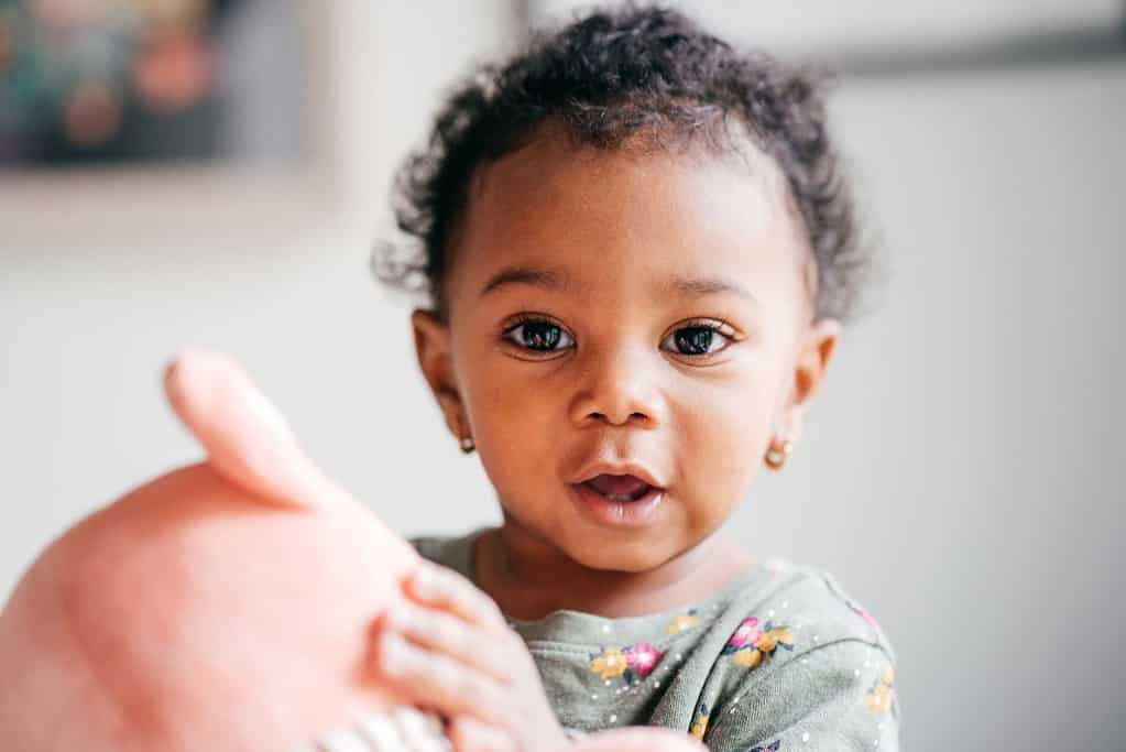 A baby touches a soft stuffed animal during a sensory play activity.