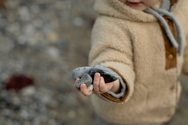 A child holds up stones during a nature play activity.