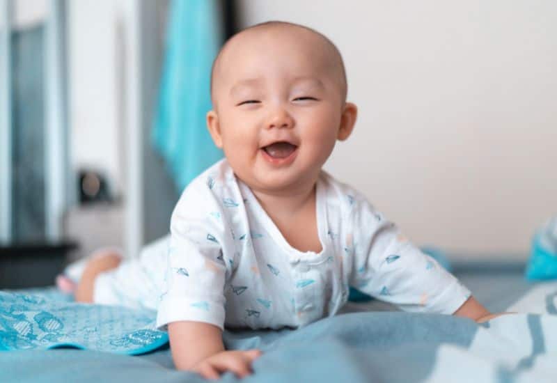 A 3-month-old baby smiles while playing during tummy time.