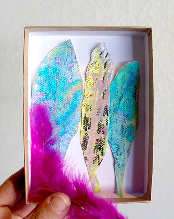 Nature drawing – hand holding pink feathers u0026 box with cut out painted feathers in it