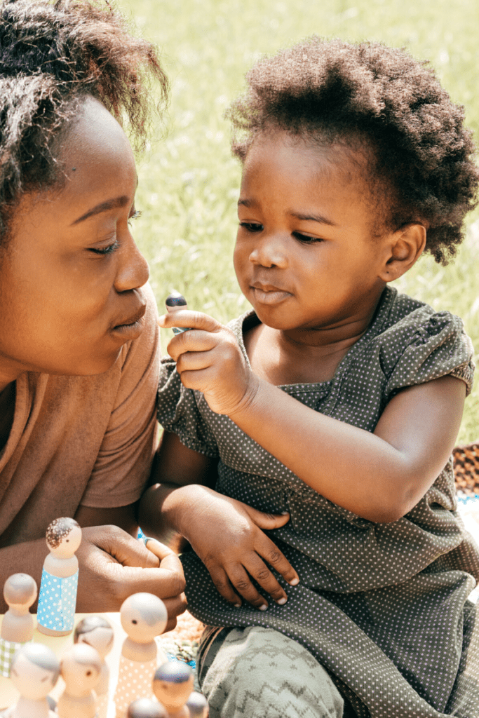 1-year-old toddler playing outdoors with mom using people toys