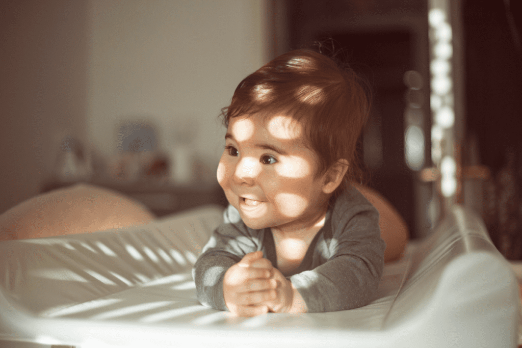 A baby explores light and shadows during a tummy time sensory activity.