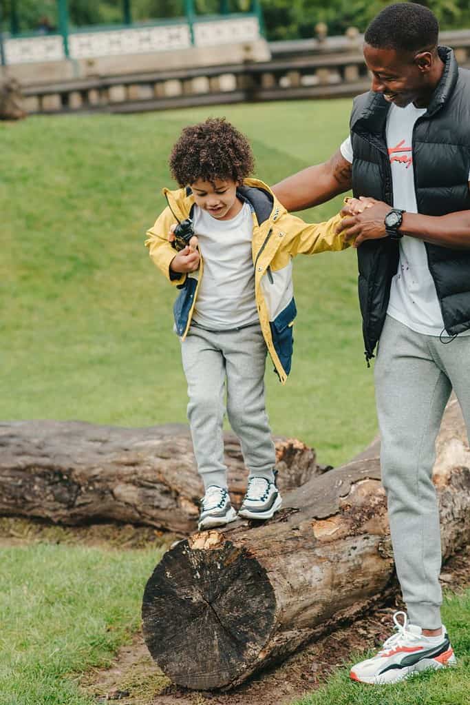 A child walks on a log during a nature play activity.