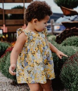 A toddler exploring red flowers.