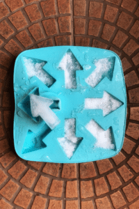 A silicone mold with arrows filled with arrow-shaped ice for ice play