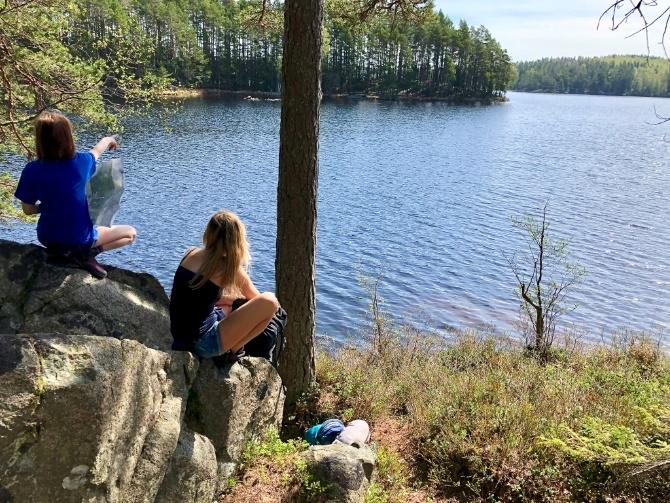 A group of people sitting on a rock by a lake

Description automatically generated with medium confidence