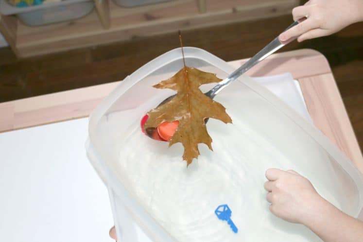 preschooler scooping objects from moving water sensory bin