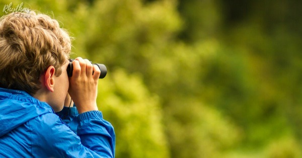 Kid looking through a pair of binoculars bird watching