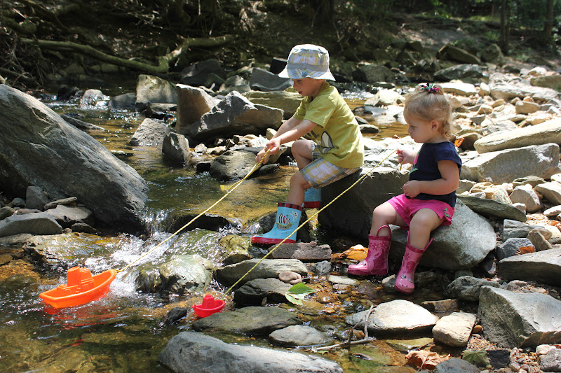 A child walks on a log during a nature play activity.