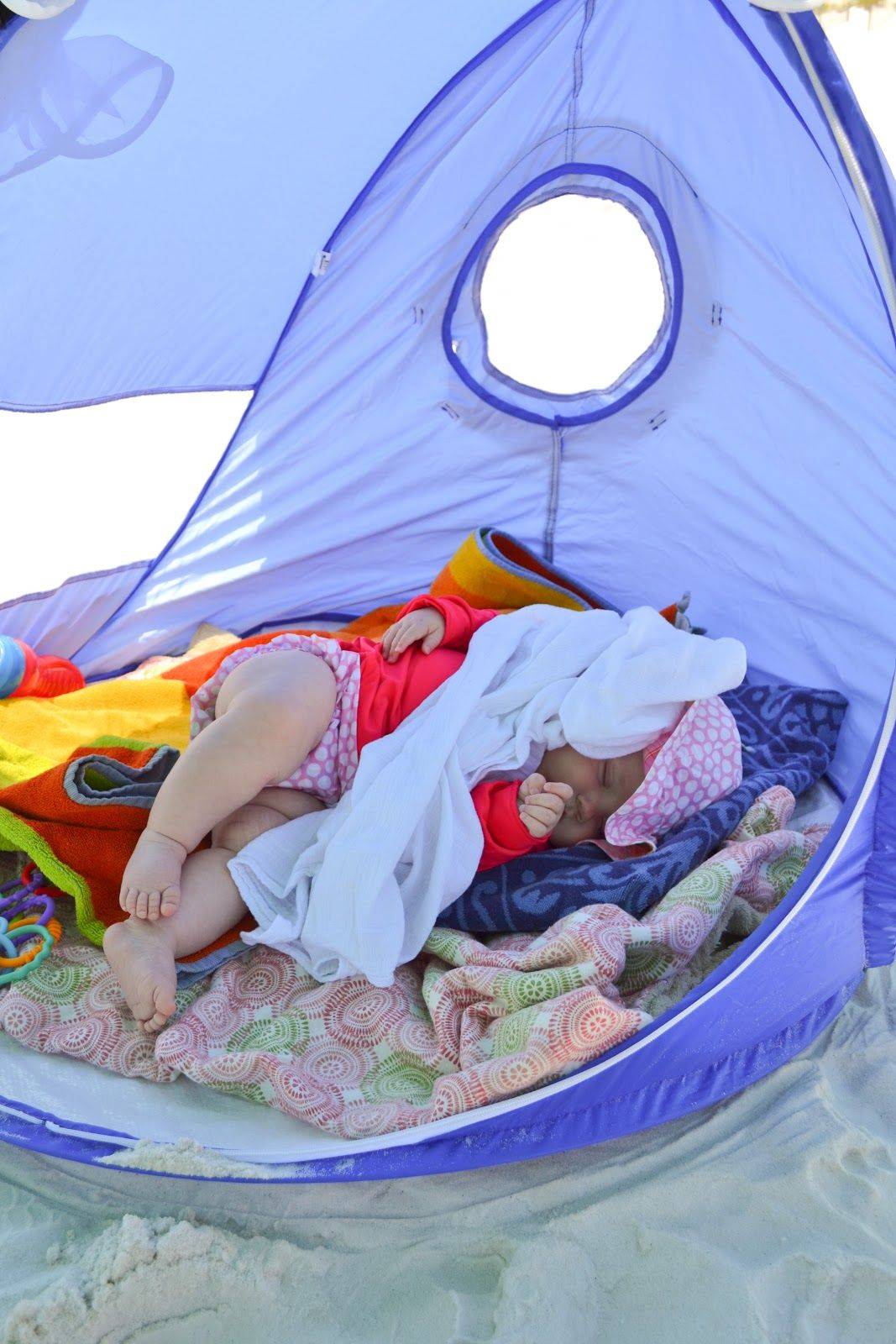 This may contain: a baby laying in a laundry basket on the beach