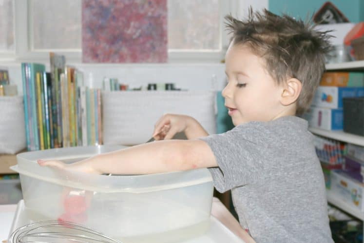 preschooler picking up object from moving water sensory bin