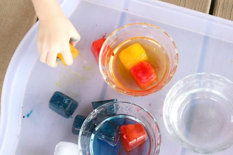 preschooler picking up yellow ice cube